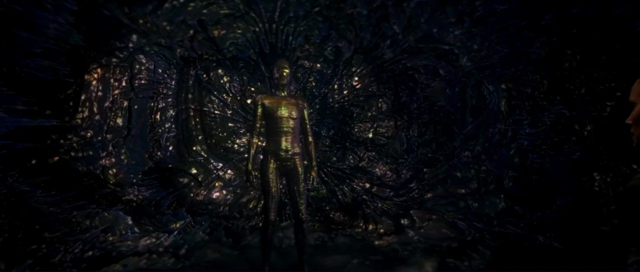 Annihilation (2018) movie still: fullbody — A dark, textured environment features organic, rib-like shapes radiating behind a central humanoid…