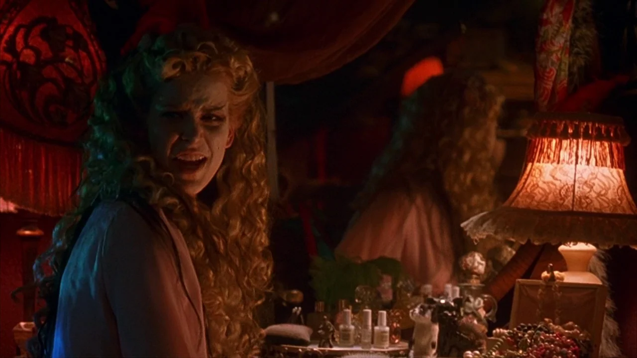 House of 1000 Corpses (2003) movie still: medium — A dimly lit room features a vanity with a warm glowing lamp. A blonde woman looks toward the side…
