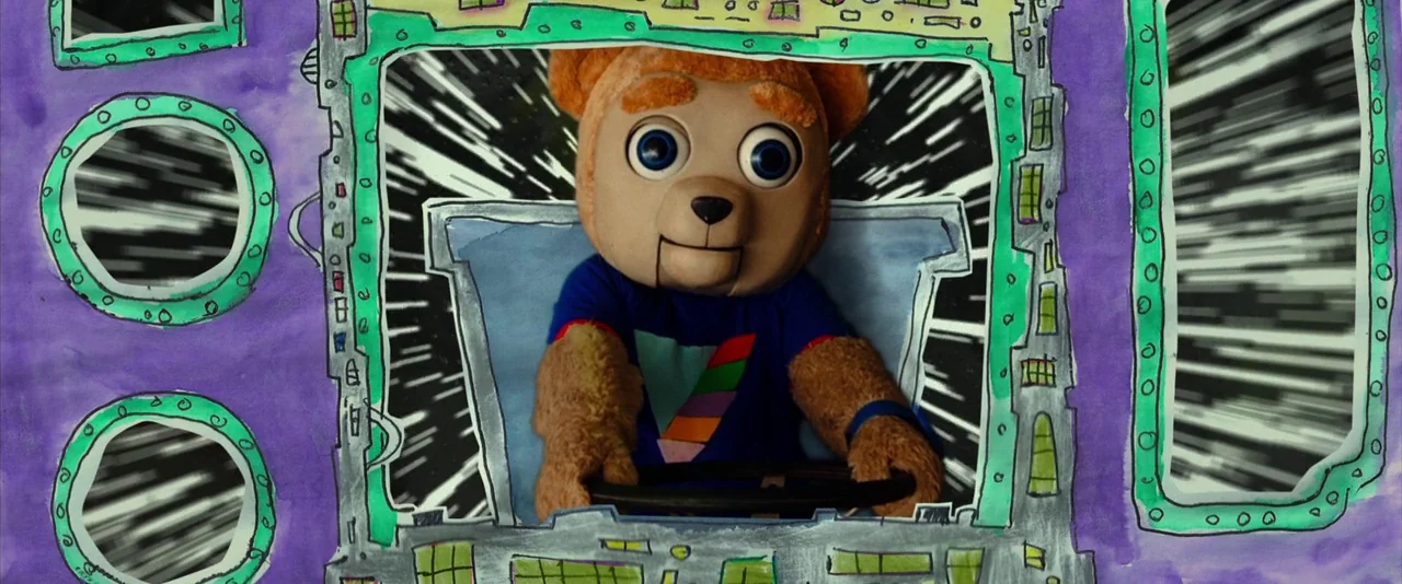 Brigsby Bear (2017) movie still: medium — A bear puppet sits at the controls of a hand-painted, flat-perspective spacecraft. Through the windows, a…