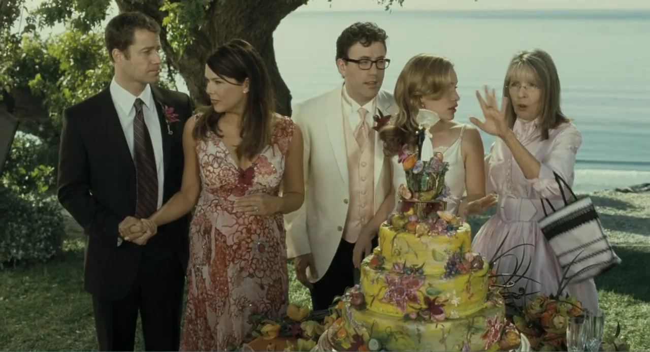 Because I Said So (2007) movie still: medium — A grassy area by the ocean hosts a group standing around a cake. Five people in formal wear interact…