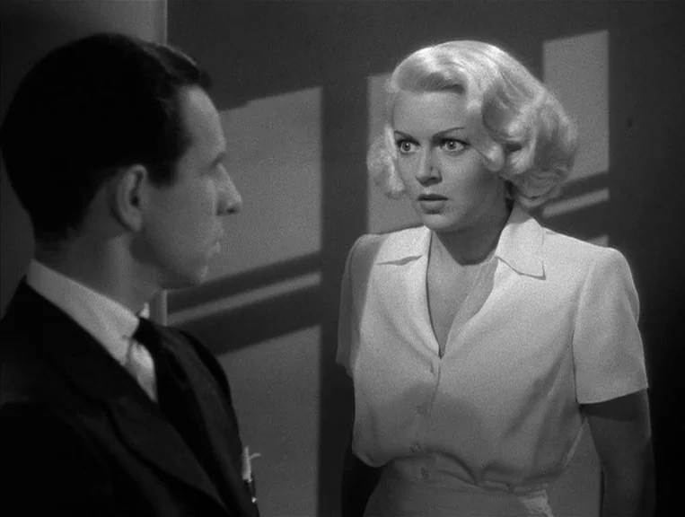 The Postman Always Rings Twice (1946) movie still: medium — An interior space features a woman in a light-colored blouse and a man in a suit. The…