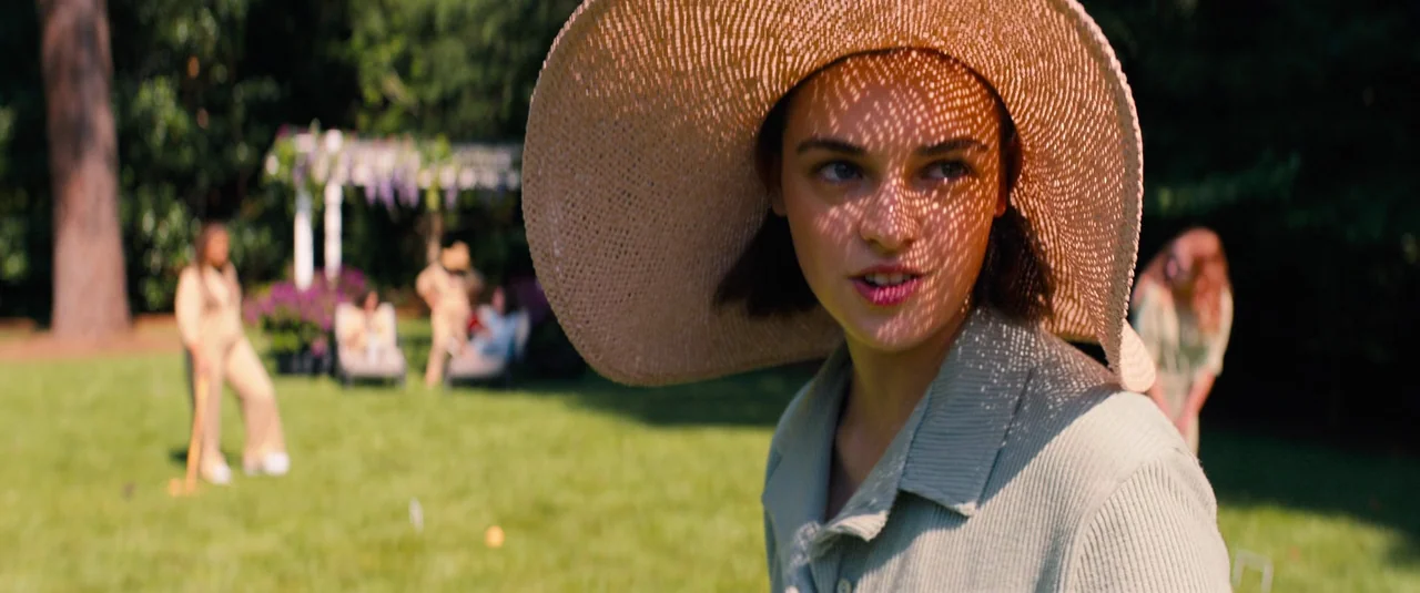 Do Revenge (2022) movie still: medium — A sunny lawn where a group of people play croquet near a white structure. A young woman in a straw hat…