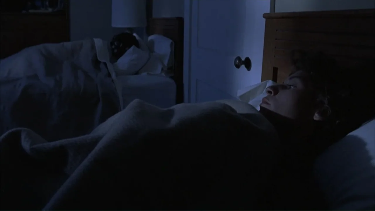 Temple Grandin (2010) movie still: medium — A dimly lit bedroom features two twin beds with wooden headboards in shadow. One person is awake in the…