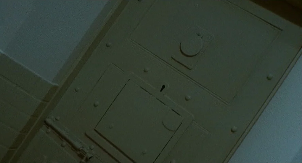 Blood From The Mummy’s Tomb (1971) movie still: closeup — A heavy metal door features a central sliding panel and a keyhole. The door is reinforced…