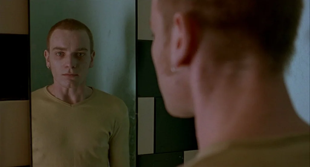 Trainspotting (1996) movie still: medium — A small bathroom with black and white checkered tiles on the wall. A young man stares directly at his…
