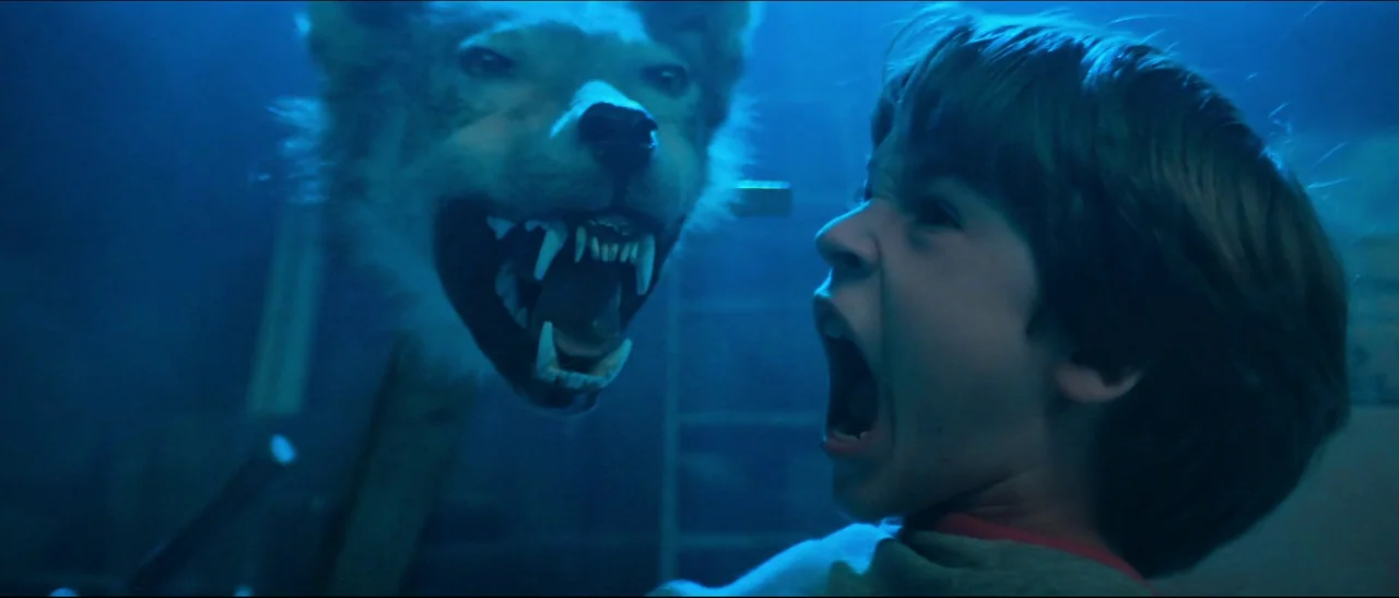 The NeverEnding Story (1984) movie still: medium — A dark, dimly lit basement is illuminated by a sharp blue light source. A young boy screams while…
