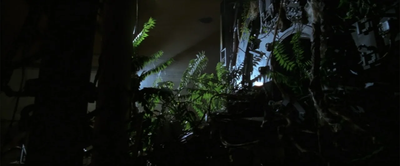 A Sound of Thunder (2005) movie still: wide — An interior space is overrun by dense tropical ferns and vines. Vegetation partially obscures a…