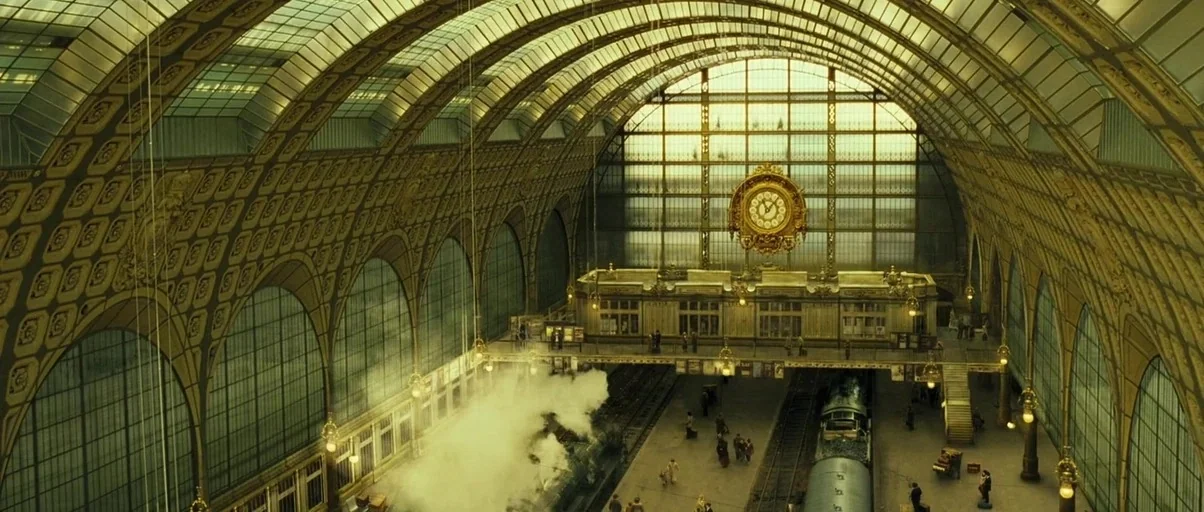 A Very Long Engagement (2004) movie still: establishing — A grand, vaulted railway terminal features an ornate iron structure and a massive central…