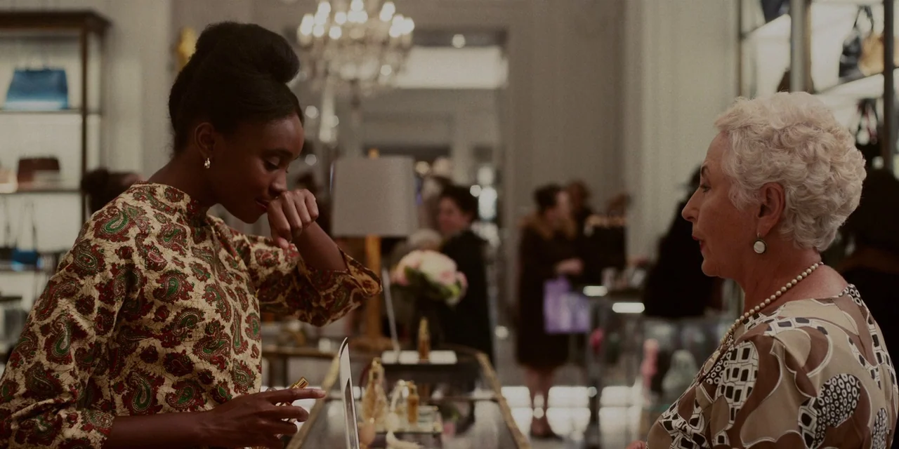 If Beale Street Could Talk (2018) movie still: medium — A high-end retail fragrance counter features glass displays and soft indoor lighting. Two…