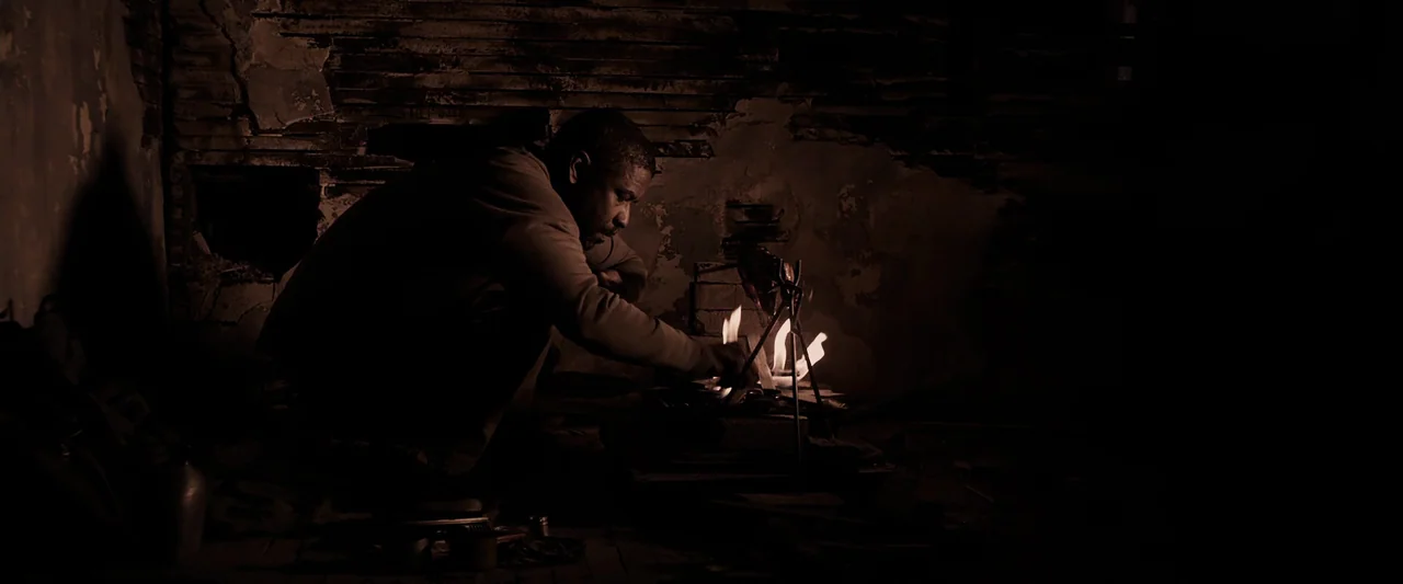 The Book of Eli (2010) movie still: medium — A dark, dilapidated space features exposed wooden wall studs and weathered plaster textures. A man…