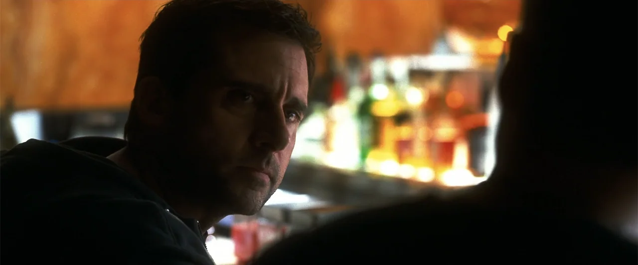 Crazy, Stupid, Love. (2011) movie still: closeup — A dimly lit bar with out-of-focus shelves of bottles in the background. A man looks sideways…