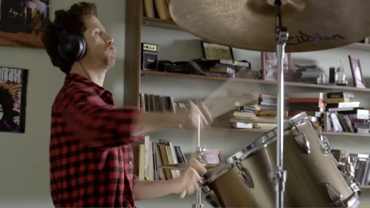 Heaven Sent (1994) movie still: medium — A residential room features wooden shelving units filled with books and music memorabilia. A man wearing a…