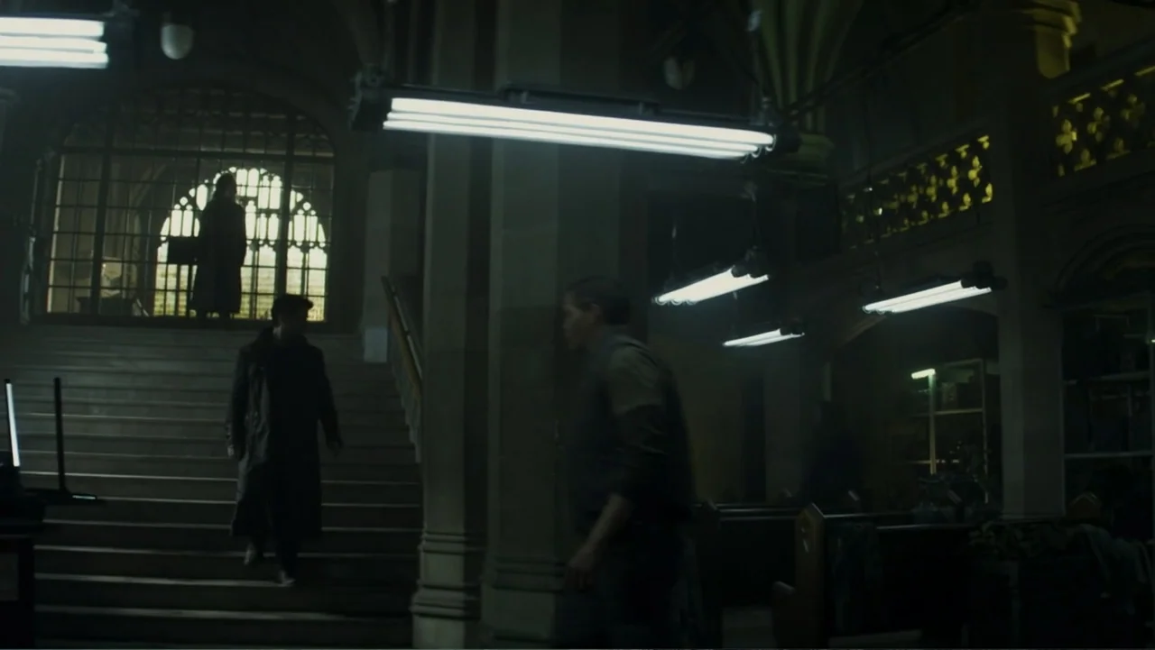 Total Recall (2012) movie still: wide — A stone cathedral interior contains dark wooden pews and arched architectural features. A man walks down…