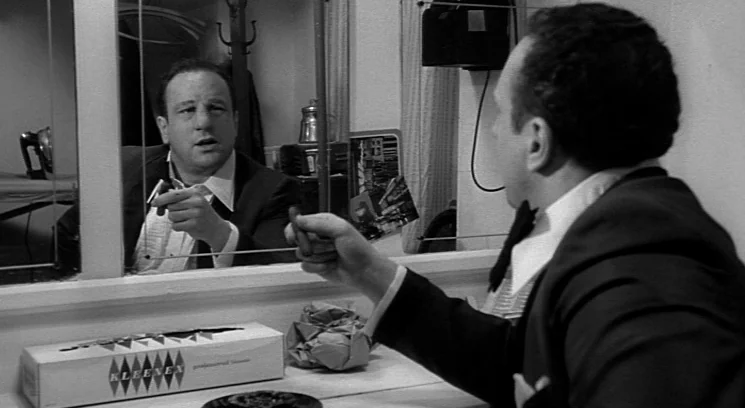 Raging Bull (1980) movie still: medium — A dimly lit backstage area featuring a vanity mirror and various personal items. A middle-aged man in a…