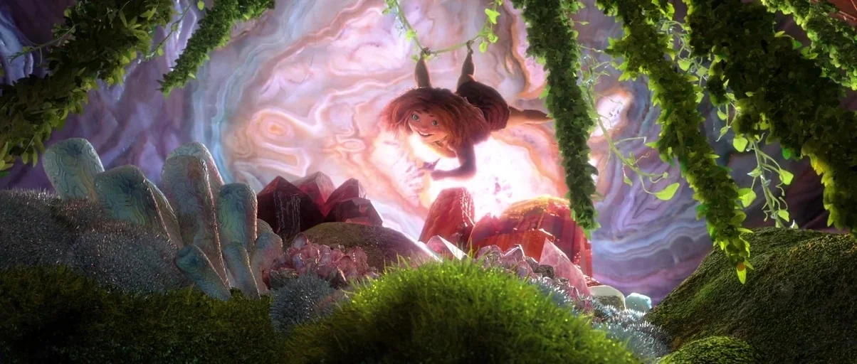 The Croods (2013) movie still: medium — A glowing, cavernous space is filled with large, textured rock formations and vibrant, moss-covered ground.…