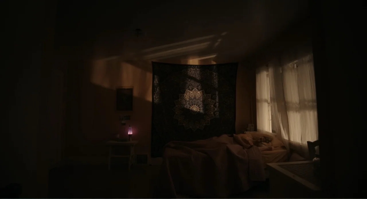 Ted Bundy: American Boogeyman (2021) movie still: wide — A dark bedroom features a bed placed beneath a large hanging tapestry wall decoration.…
