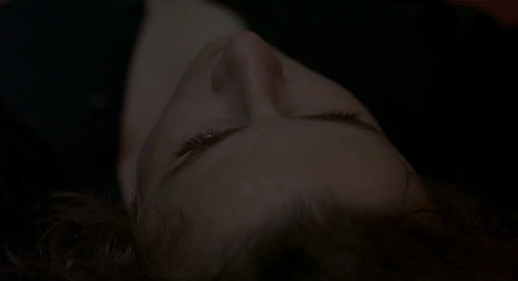 Vendredi Soir (2002) movie still: closeup — A dimly lit, dark environment surrounds the face of a sleeping individual. The subject lies with eyes…