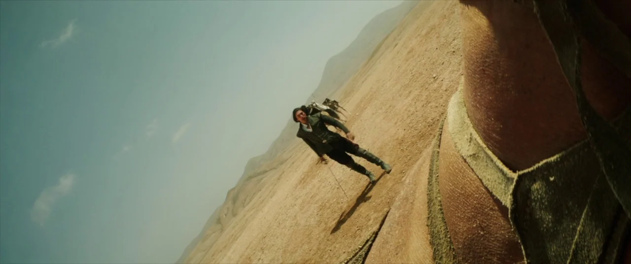 The Man Who Killed Don Quixote (2018) movie still: wide — A vast, dry desert landscape stretches under a pale blue sky during midday. A man in a…