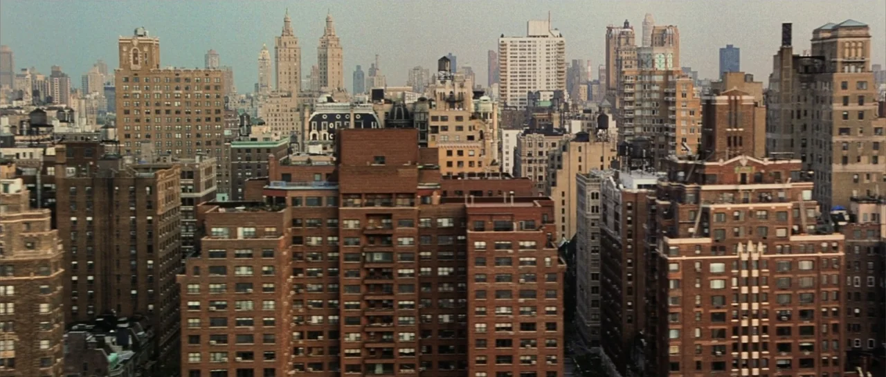 Daredevil (2015) movie still: establishing — A dense urban landscape features rows of historic brick apartment buildings and towers. The perspective…