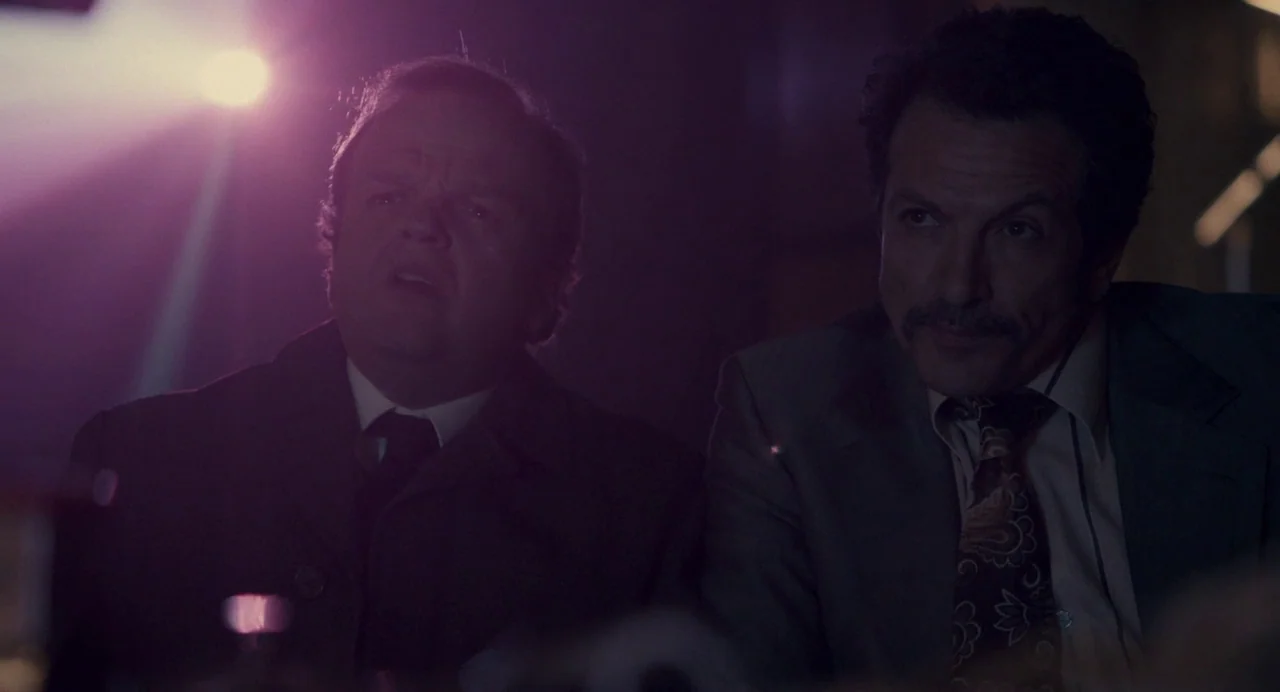 Berberian Sound Studio (2012) movie still: medium — Two men watch a film in a dark, dimly lit theater space. The light from the projector casts a…