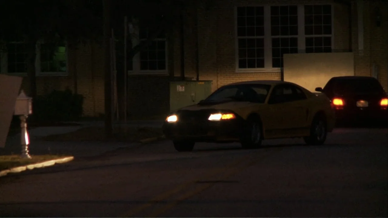 12th & Delaware (2010) movie still: wide — A dark residential street is lit by the headlights of a yellow sports car. A black sedan is parked nearby…
