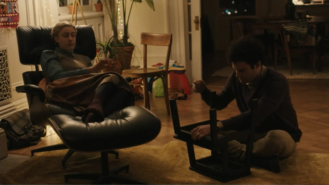 Maggie's Plan (2016) movie still: medium — A well-lit residential room features hardwood floors, houseplants, and a classic leather lounge chair. A…