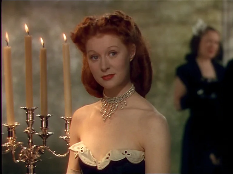 The Red Shoes (1948) movie still: medium — An interior space features a candlelit atmosphere in a classic historical setting. A woman with red hair…