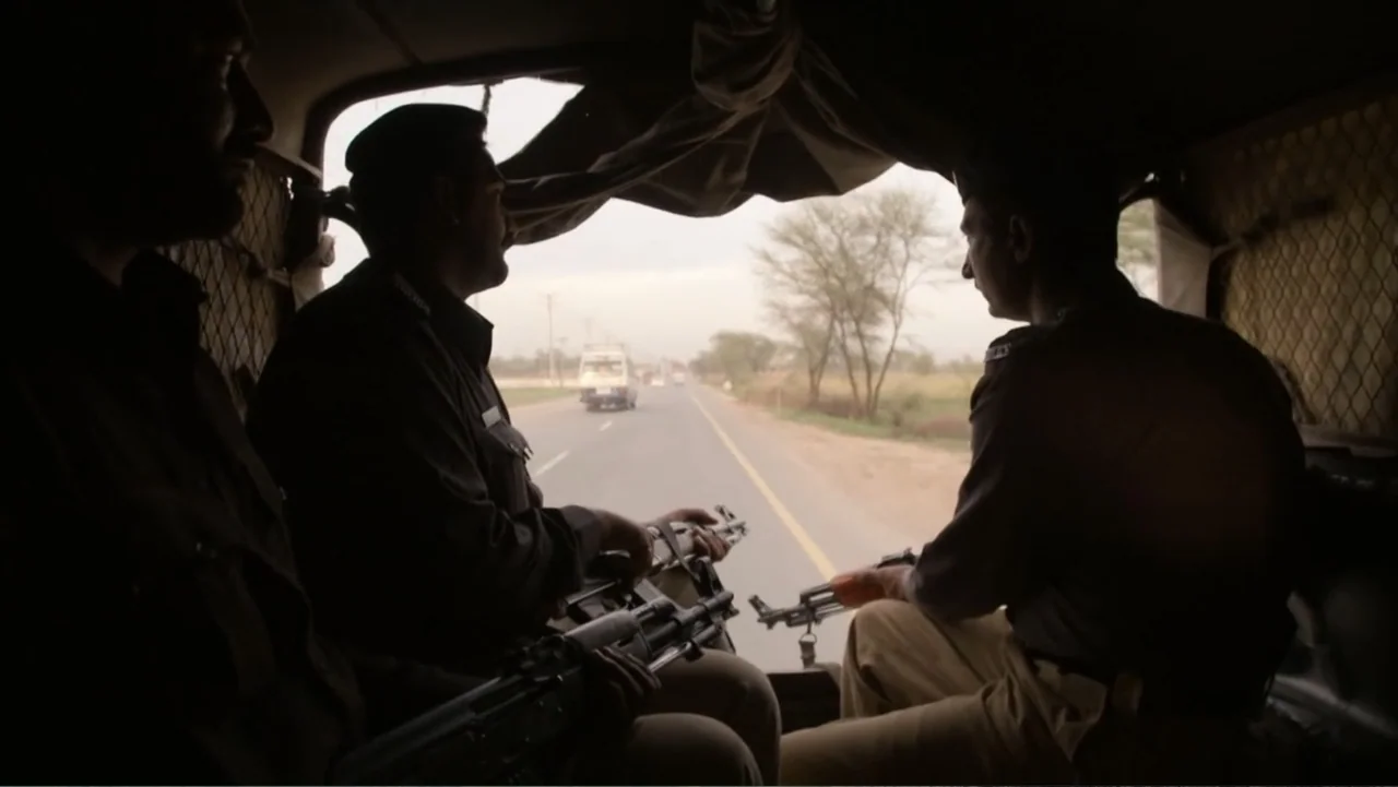 A Girl in the River: The Price of Forgiveness (2015) movie still: medium — The interior of a moving transport vehicle looking out toward a paved…