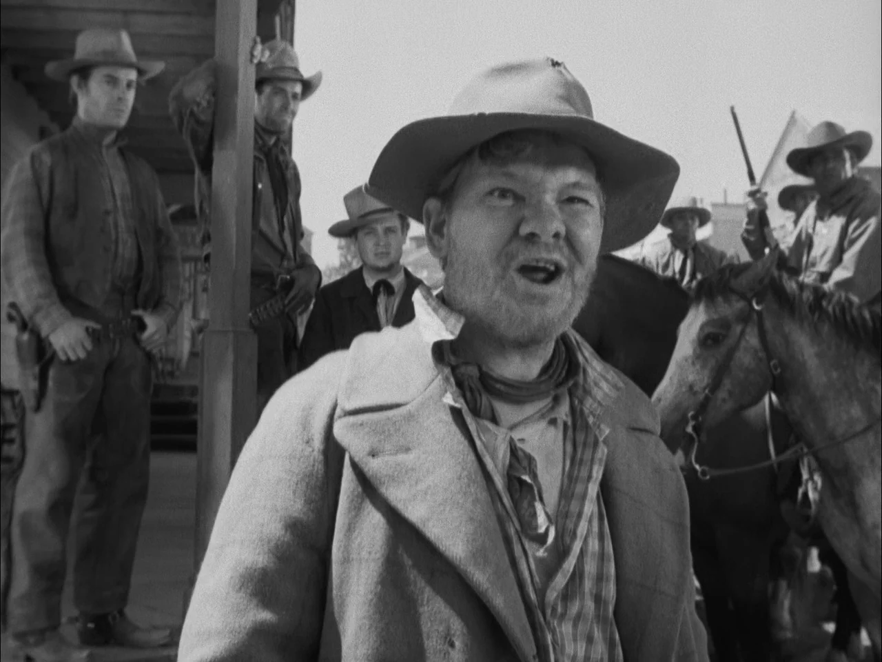 The Ox-Bow Incident (1942) movie still: medium — A dusty outdoor wooden porch in an Old West town setting with several men. A man in a felt hat…