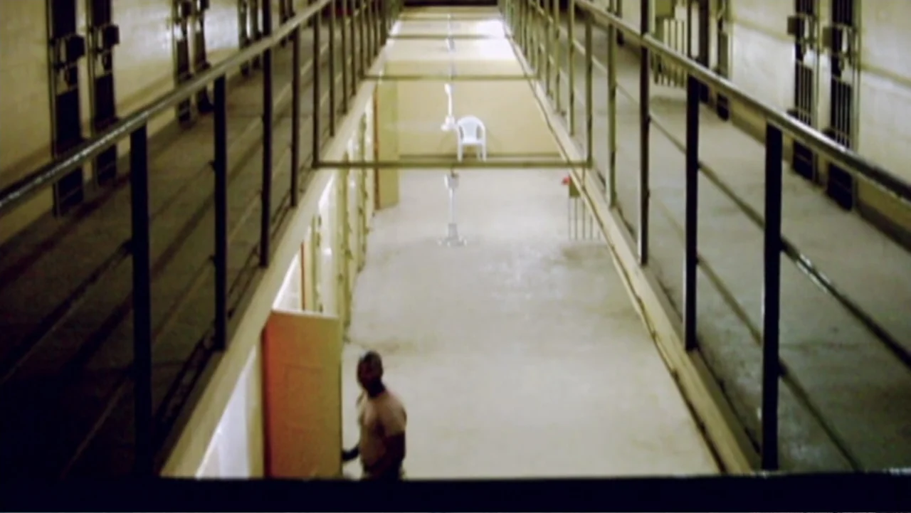 Ghosts of Abu Ghraib (2007) movie still: wide — A long, multi-level prison cell block features yellow walls and black iron metal railings. A…