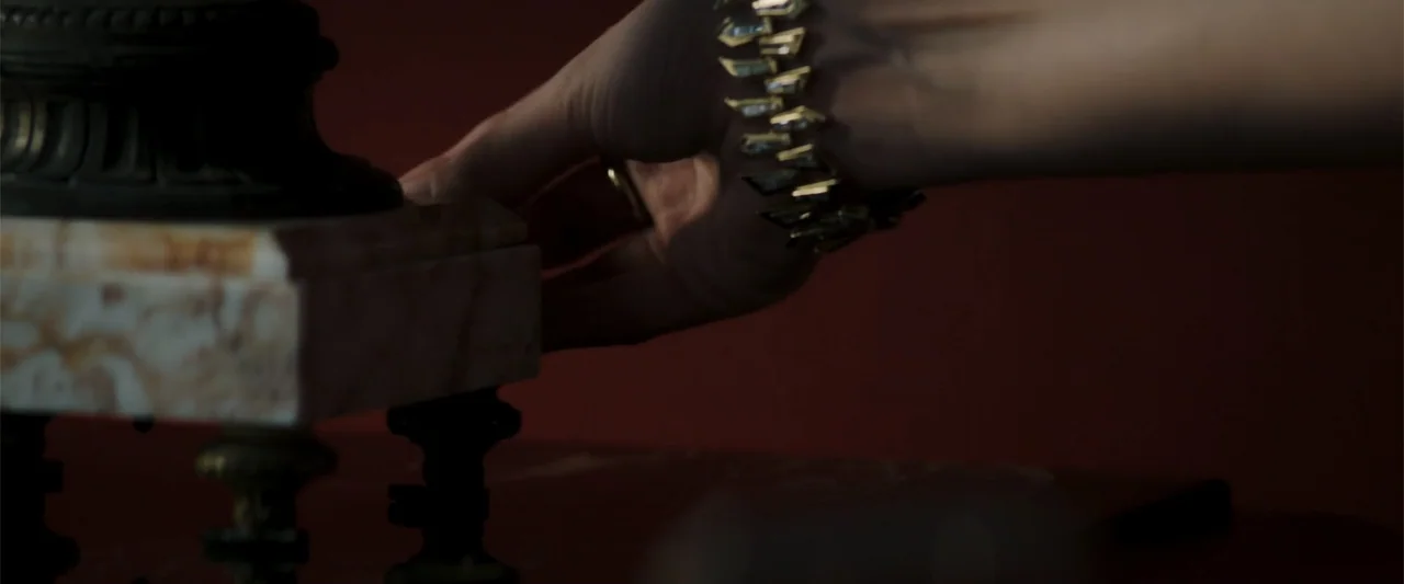 Operation Fortune: Ruse de Guerre (2023) movie still: closeup — A dark indoor space features a marble-based object on a surface. A hand wearing a…