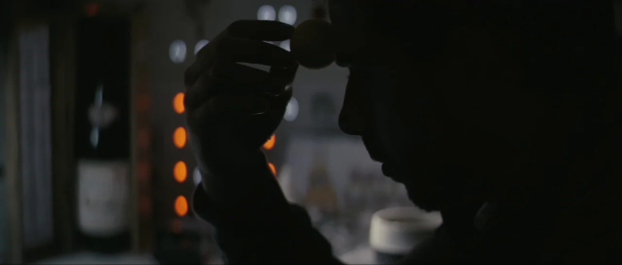 The Last Days On Mars (2013) movie still: closeup — A dark indoor space contains a man partially obscured in silhouette against distant lights. The…