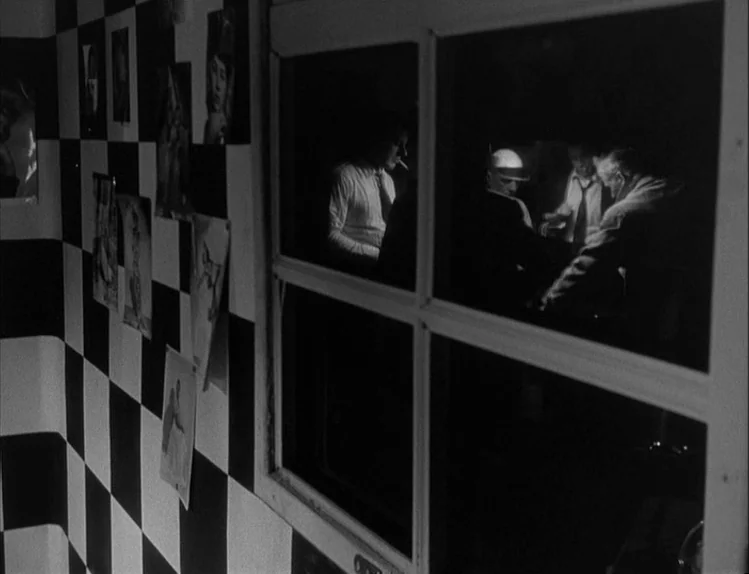 Bob le Flambeur (1956) movie still: medium — A checkerboard-patterned wall with various photographs hanging adorns a room next to a window. Through…