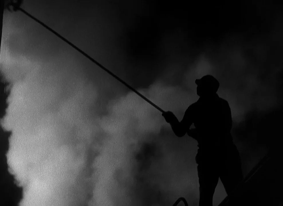 Shanghai Express (1932) movie still: medium — A dark, silhouetted figure stands against a bright, cloudy sky at night. The person holds a long pole…