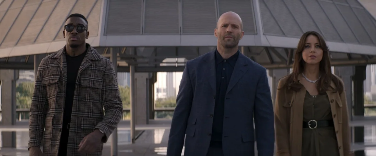 Operation Fortune: Ruse de Guerre (2023) movie still: medium — A modern concrete plaza features a prominent angular glass and metal overhead…