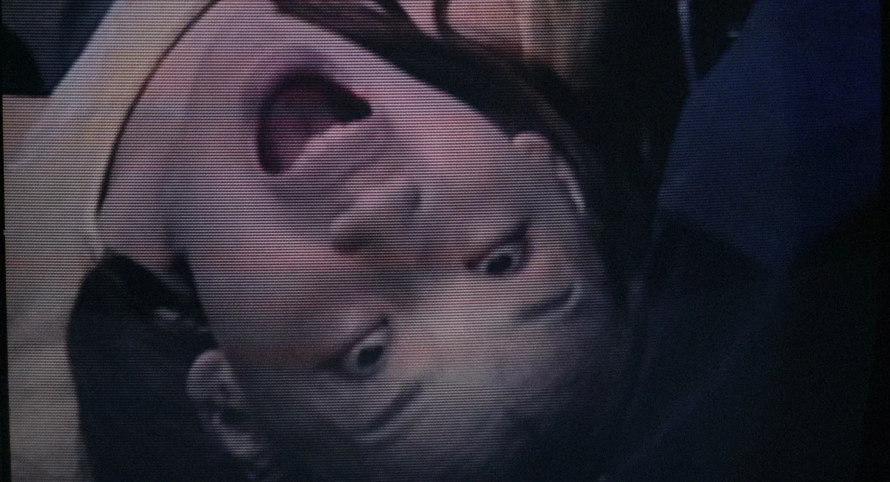 Ringu (1998) movie still: closeup — A close-up view shows a person's head oriented upside down within a dark space. The subject stares directly into…