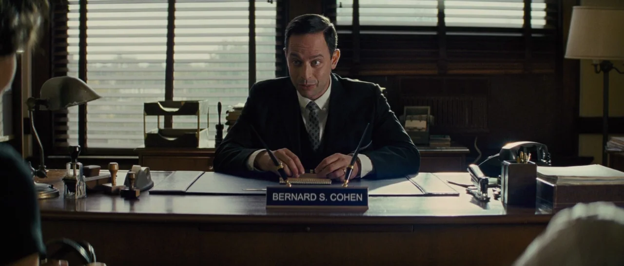 Loving (2016) movie still: medium — A wood-paneled office from the mid-20th century features a nameplate on a mahogany desk. A man in a suit sits…