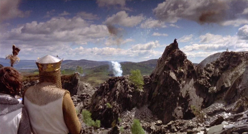 Monty Python and the Holy Grail (1975) movie still: wide — A rugged mountainous landscape features steep rocky cliffs and sparse green vegetation.…