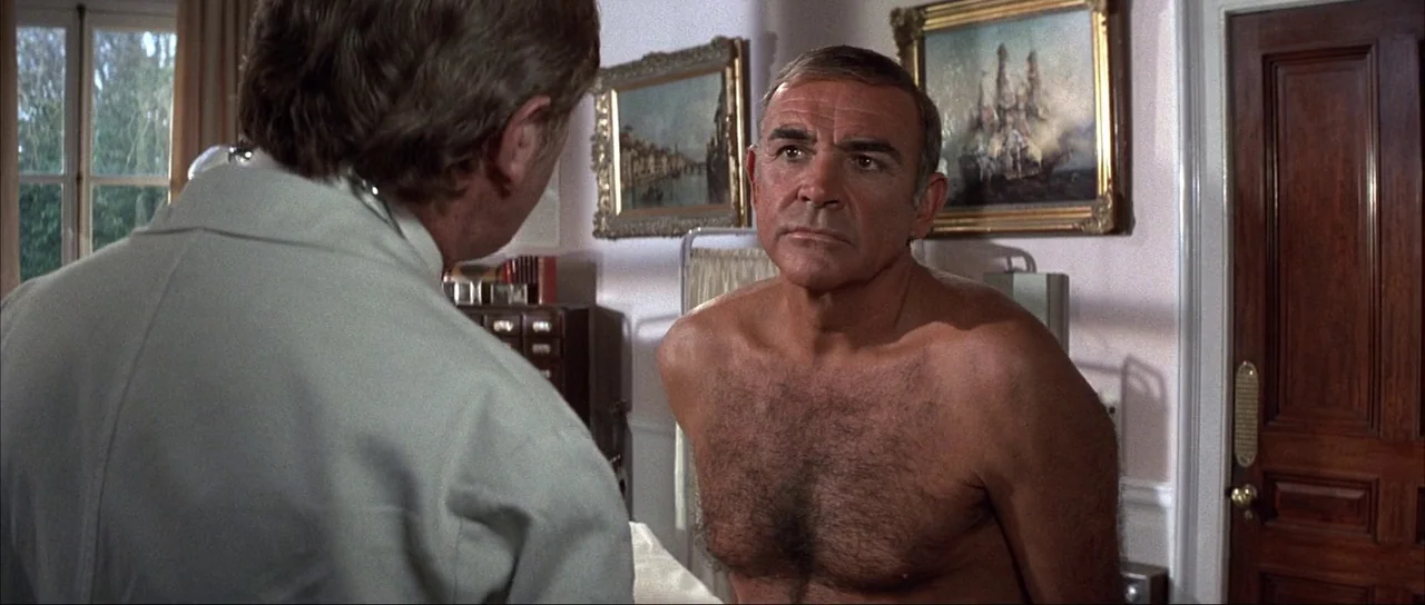 Never Say Never Again (1983) movie still: medium — A medical office with light-colored walls adorned with two framed landscape paintings. A…
