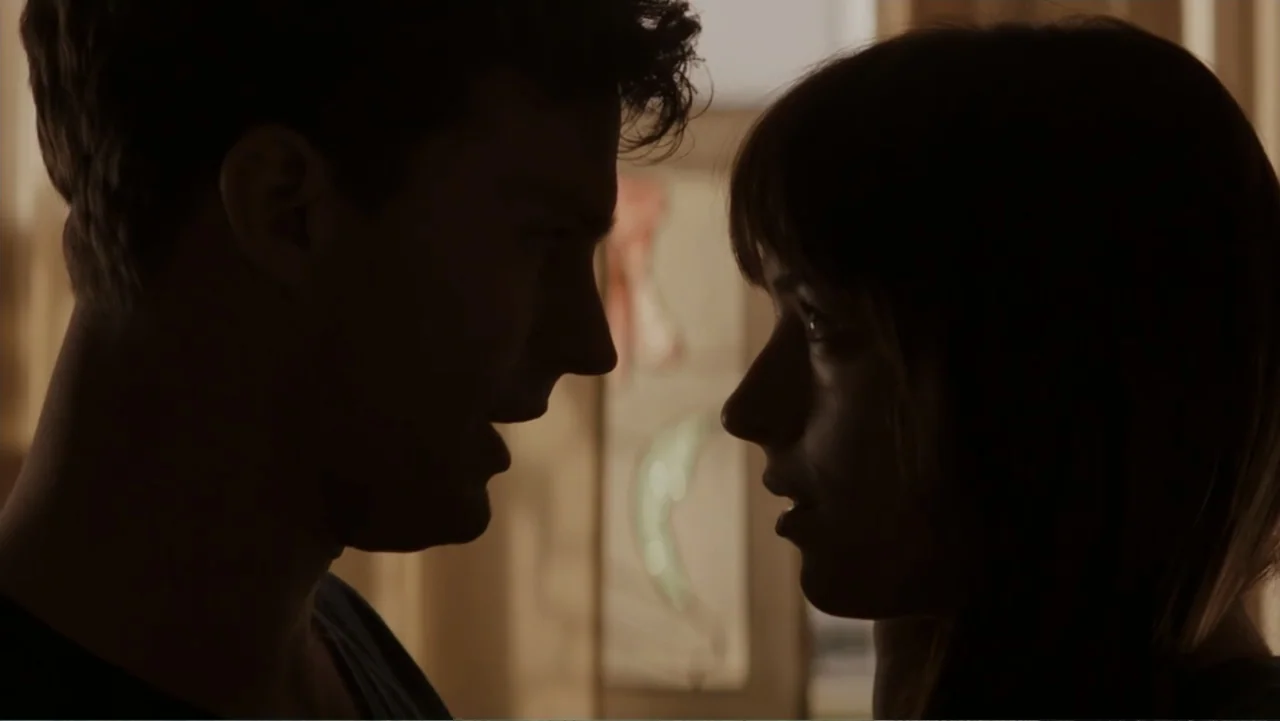 Fifty Shades of Grey (2015) movie still: medium — A dimly lit indoor space with silhouettes against a window background. A man and a woman stand…