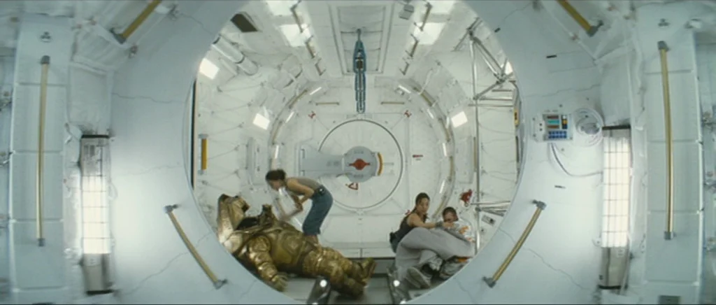 Sunshine movie still: wide — A circular white spacecraft module features padded walls and integrated lighting panels. Three people gather around a…