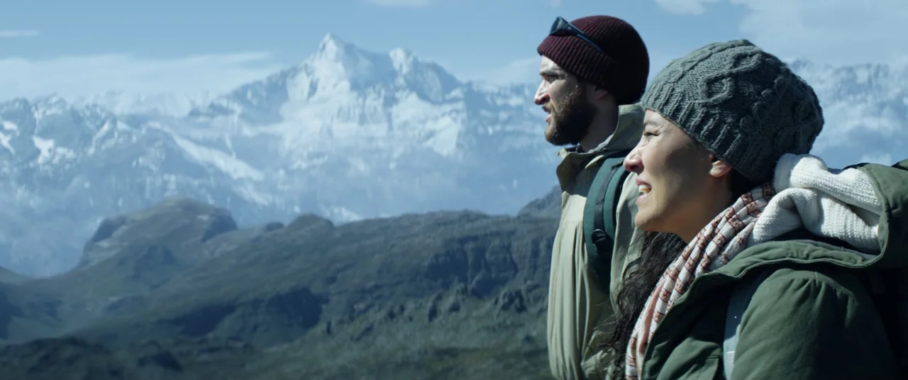 The Empty Man (2020) movie still: medium — Two hikers stand on a high mountain ridge overlooking a large snowy peak. The couple looks into the…