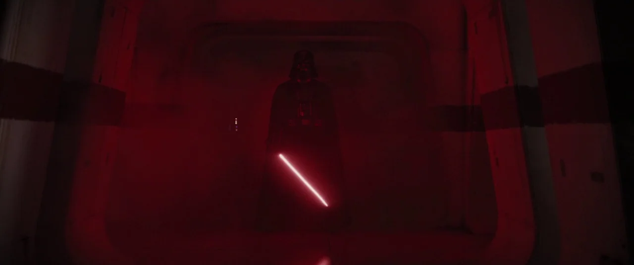 Rogue One: A Star Wars Story (2016) movie still: fullbody — A dark, dimly lit metal hallway is filled with thick red smoke. Darth Vader stands…