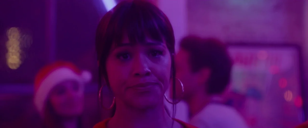 Someone Great (2019) movie still: closeup — A crowded indoor party space is filled with purple and magenta neon ambient light. A young woman with…