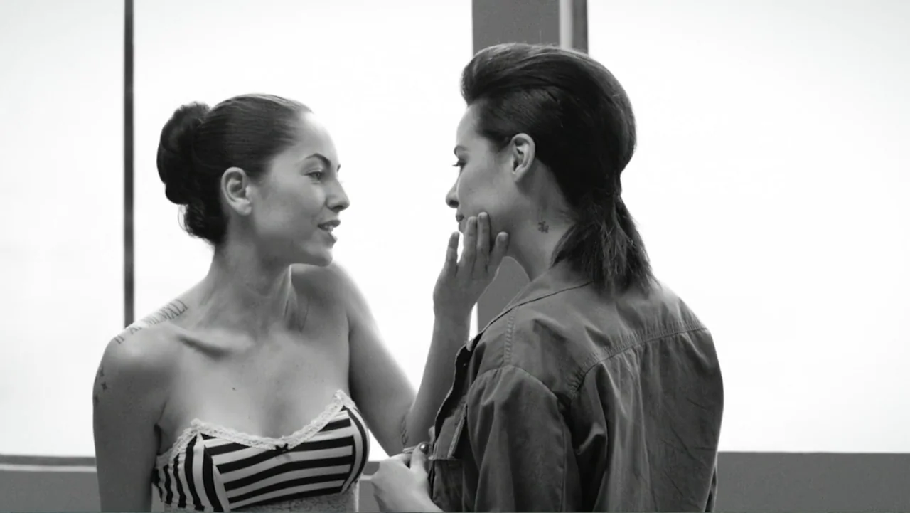 Alice in Marialand (2014) movie still: medium — A bright studio interior with a neutral white background and two women facing each other. The woman…