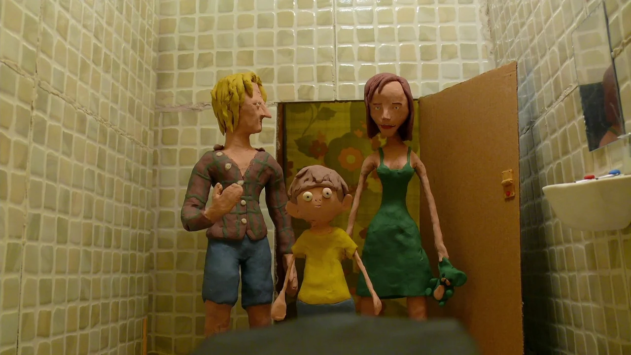 The ABCs of Death (2012) movie still: fullbody — A tiled bathroom with a small sink and cardboard door backdrop. Three clay stop-motion figures…