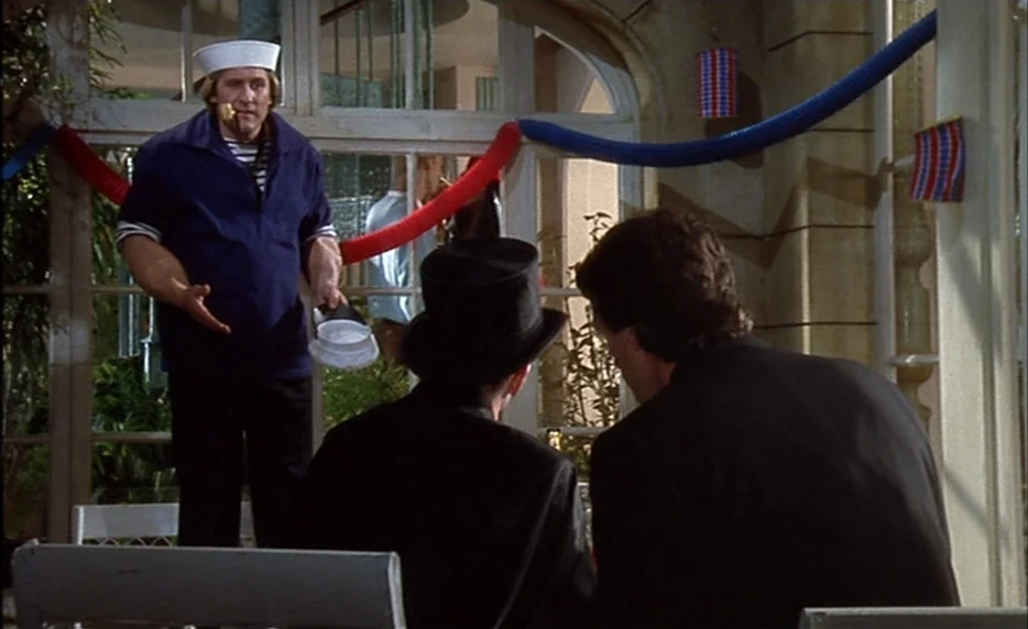 I Want To Go Home (1989) movie still: medium — A glass-walled sunroom is decorated with red and blue paper streamers for a celebration. A man…