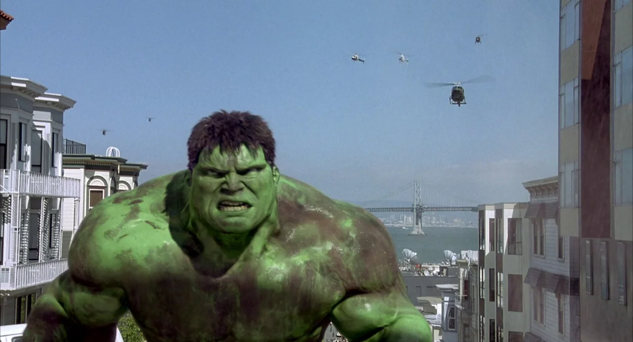 Hulk (2003) movie still: medium — A gargantuan green humanoid figure towers over a dense San Francisco residential district. Multiple military…