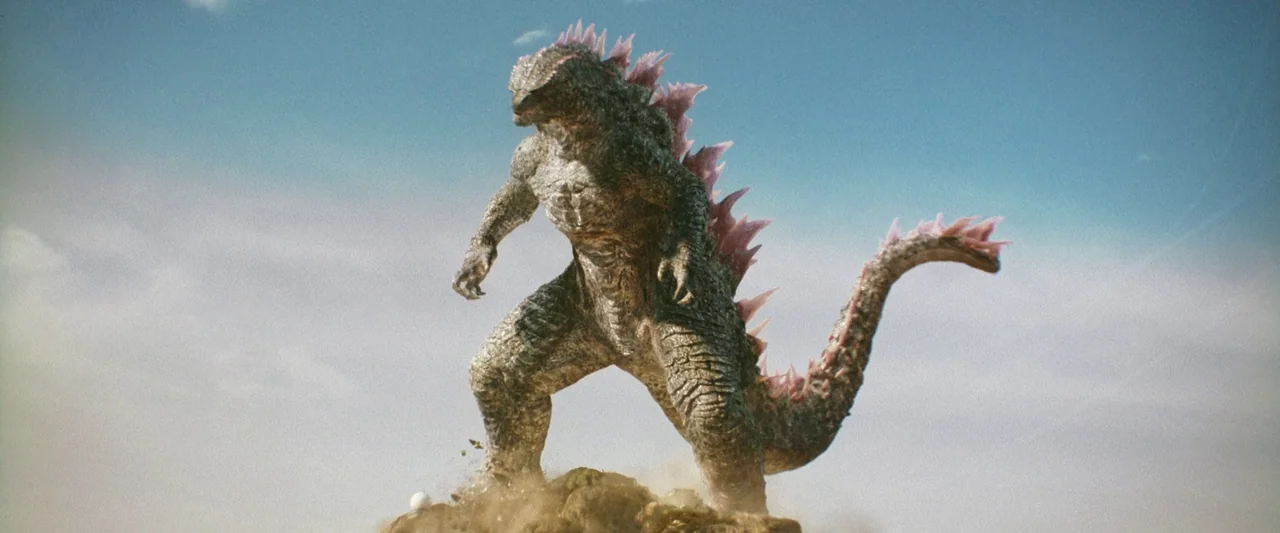 Godzilla x Kong: The New Empire (2024) movie still: fullbody — A gargantuan reptilian creature stands upon a dusty, rocky mound against a clear sky.…