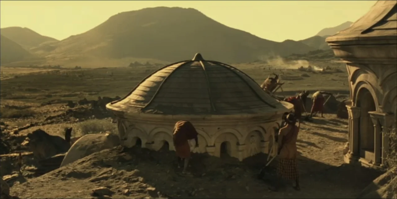 Exorcist: The Beginning (2004) movie still: wide — A dry, mountainous landscape contains a partially buried stone rotunda at an excavation site.…